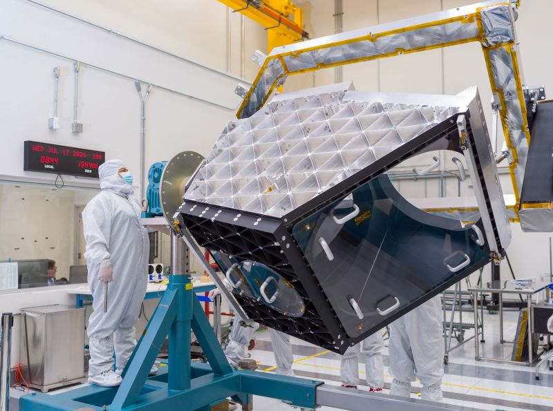 A technician operates articulating equipment to rotate NEO Surveyor’s aluminum optical bench